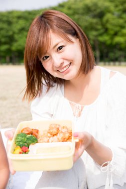 Piknikte atıştırmalık taşıyan Asyalı kadın.