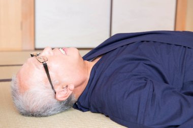 Olgun Asyalı adam yerde dinleniyor.