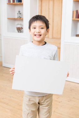 Gülümseyen çocuk boş beyaz tuval tutuyor.