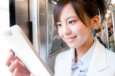 Metroda tablet kullanan genç Asyalı kadın.