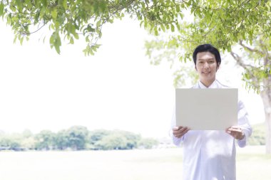 Parkta elinde beyaz bir ilan panosu olan bir adam.