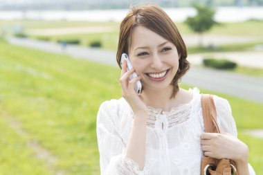 Parkta cep telefonu kullanan çekici Asyalı kadın portresi.