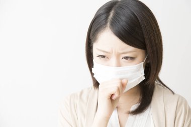 Soluk maskeli hasta bir Asyalı kadının portresi beyaza izole edilmiş.