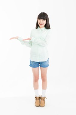 Genç Asyalı kız beyaz arka planda avuçları açık bir şey gösteriyor. 