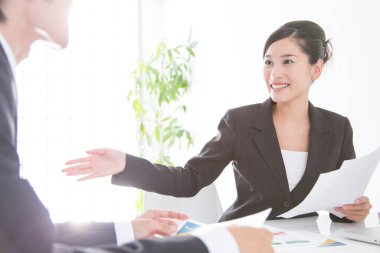 Genç ve güzel Japon iş kadınının portresi beyazların arasında izole edilmiş bir şekilde iş arkadaşıyla konuşuyor.