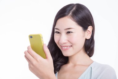 Beyaz arka planda izole edilmiş akıllı telefon kullanan gülümseyen genç Asyalı kadın. Stüdyo çekimi