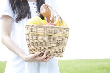 Bahçede meyve dolu sepeti tutan kadın.