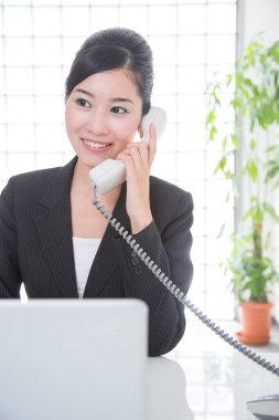 Genç Asyalı iş kadını telefonda konuşuyor. 