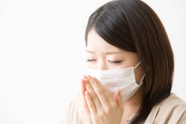 Soluk maskeli hasta bir Asyalı kadının portresi beyaza izole edilmiş.