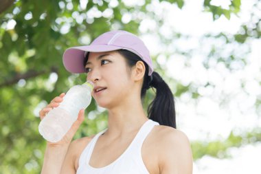 Yaz parkında koşu yaparken su içen güzel Japon kadın. 