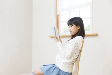 Asyalı kız oturma odasında kitap okumak