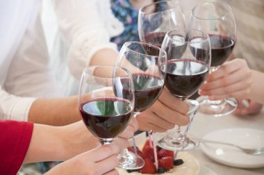 Bir grup insan kırmızı şarap içiyor.