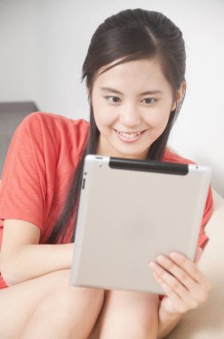 Evde tablet kullanan genç bir kadın. 