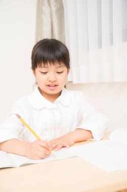 Küçük Asyalı kız ödevini yapıyor. 