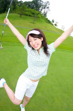 Güzel Asyalı kadın golfçü sahada poz veriyor.