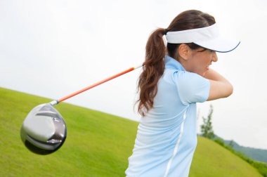 Genç Asyalı kadın golf oynuyor.