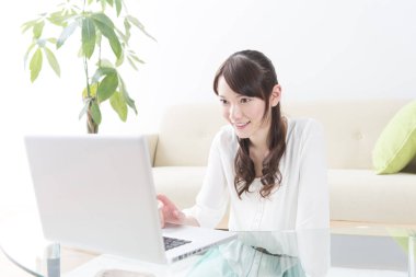 Evde dizüstü bilgisayar kullanan Asyalı genç bir kadın. 