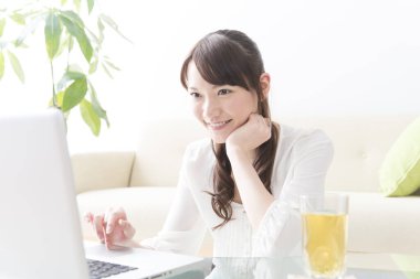 Evde dizüstü bilgisayar kullanan Asyalı genç bir kadın. 