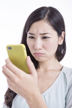 Zeki telefon kullanan mutlu, genç bir Asyalı kadın, beyaz arka planda izole edilmiş. Stüdyo çekimi