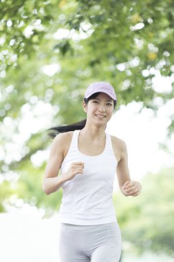 Spor yapan Japon kadın yaz parkında koşuyor. 