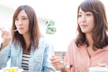 Kafede yemek yiyen iki Asyalı kadın. 