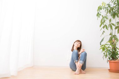 Genç ve güzel bir kadın, gündelik giysiler içinde yerde oturuyor. 