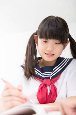 Okul üniformalı gülümseyen Japon öğrenci okulda ders çalışıyor.