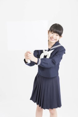Okul üniformalı güzel bir öğrencinin portresi beyaz arka planda boş bir poster tutuyor.