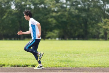 Sportif Japon adam yaz parkında koşuyor. 