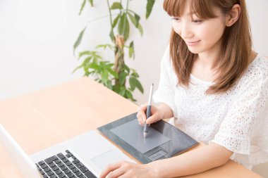 Dizüstü bilgisayar ve grafik tableti ile çalışan kadın grafik tasarımcısı