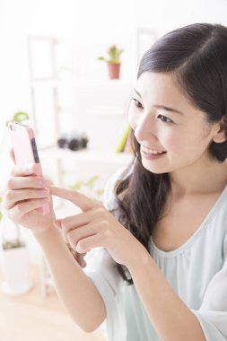 Evde akıllı telefon kullanan bir kadın.