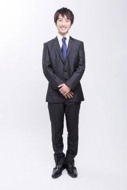 Siyah takım elbiseli Asyalı genç işadamı gülümsüyor 