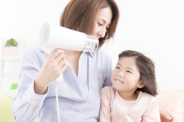 Saç kurutma makinesiyle Asyalı anne ve kızı. 