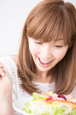 Gülümseyen Japon kadın taze salata tabağıyla