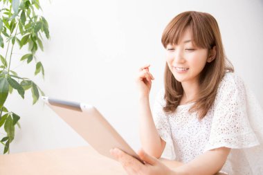 Evde tablet bilgisayar kullanan genç bir kadın. 