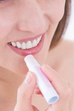 Güzel, olgun Asyalı bir kadının dudak kremi sürerken portresi.