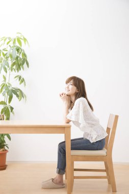 Asyalı kadın oturma odasında masada oturuyor.