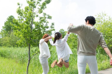 Mutlu Asyalı anne, baba ve kız parkta birlikte vakit geçiriyorlar.