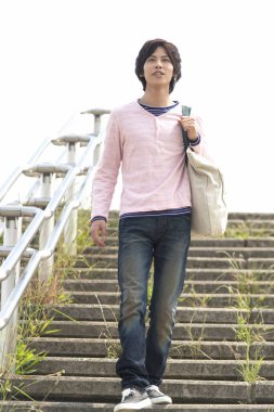 Çantalı genç adam merdivenlerden iniyor. 