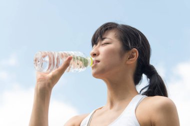 Yaz parkında koşu yaparken su içen güzel Japon kadın. 