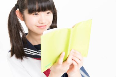 Okul üniformalı, beyaz arkaplan üzerine kitabı olan güzel bir öğrencinin portresi.