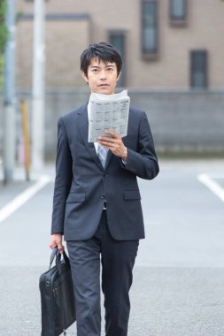 Şehirde yürüyen gazeteli bir işadamı