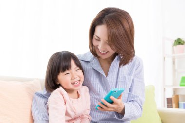 Evde cep telefonu olan Asyalı bir anne ve kız.