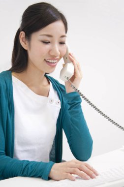 dizüstü bilgisayarda çalışan ve telefonda konuşurken genç kadın 