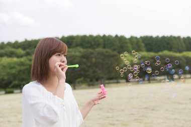 Genç bir kadın sabun köpüğü üflüyor.