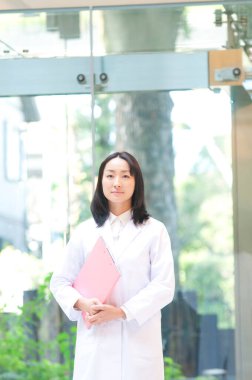 Laboratuvar önlüğü giymiş genç bir kadının portresi.