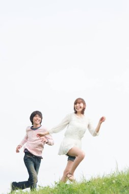 Mutlu genç Asyalı çift yaz parkında koşuyor