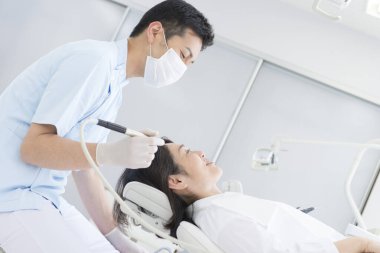 Diş hekimi muayenehanesinde hastanın dişlerini tedavi eder.