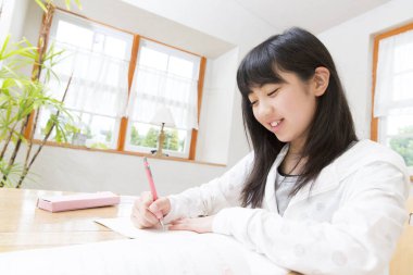 Asyalı öğrenci kız evde ders çalışıyor.