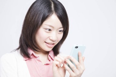Açık arkaplanda akıllı telefonu olan güzel bir Japon kadının portresi.
